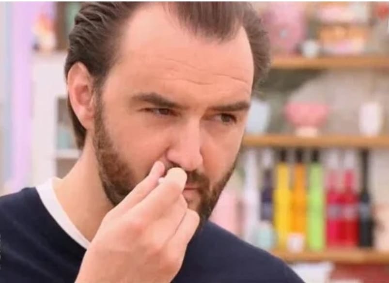 Capture d’écran de l’émission Le meilleur pâtissier où l’on voit le chef cuisinier Cyril Lignac qui goûte le gâteau d’un des participants en fronçant les sourcils.
