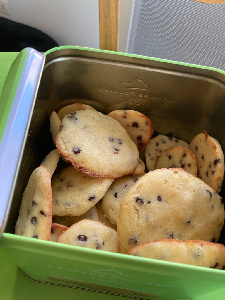 Une boîte en fer contenant plein de cookies faits maison.