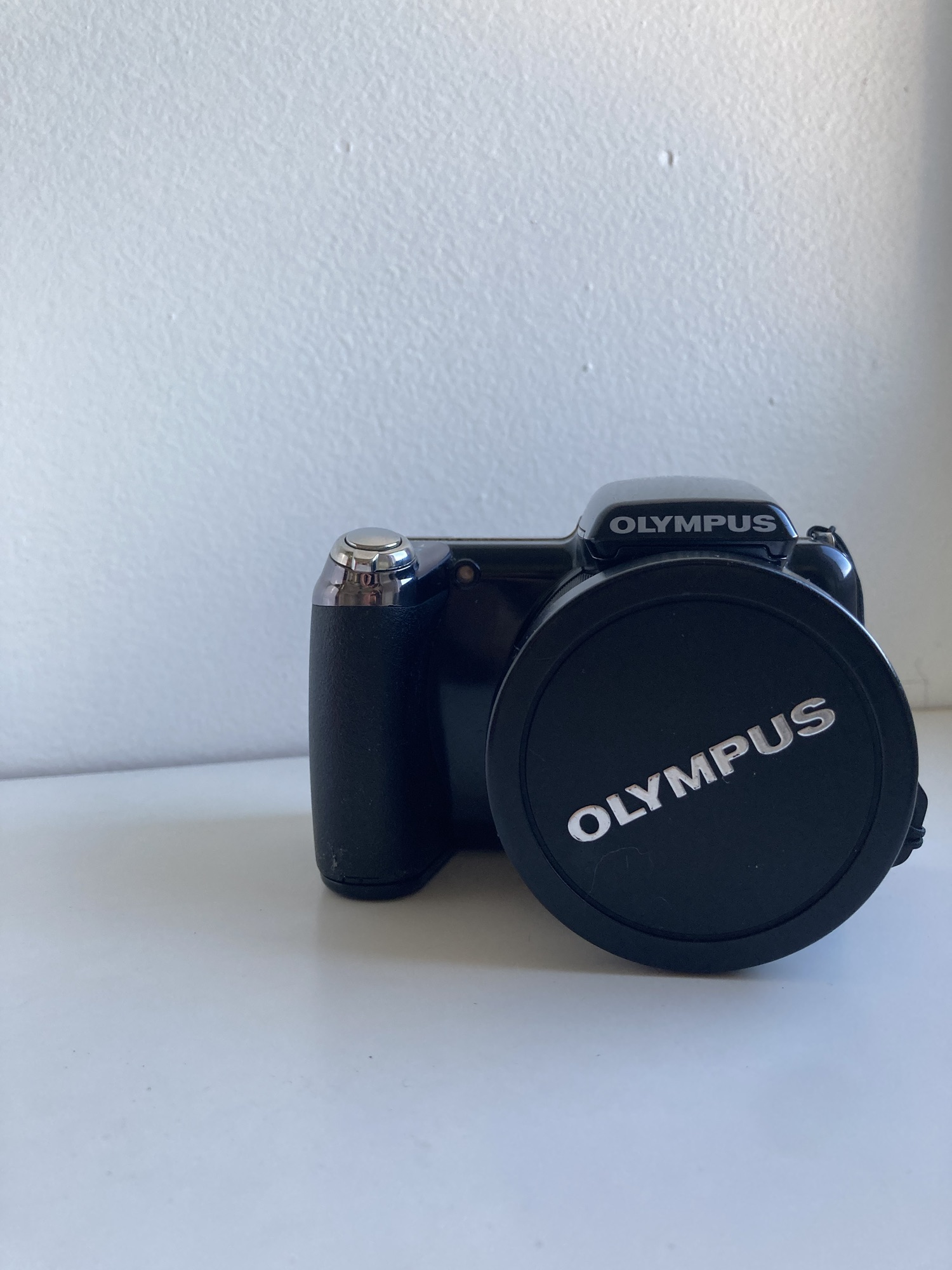 Un gros appareil photo noir avec un cache-objectif sur lequel est écrit « Olympus ».