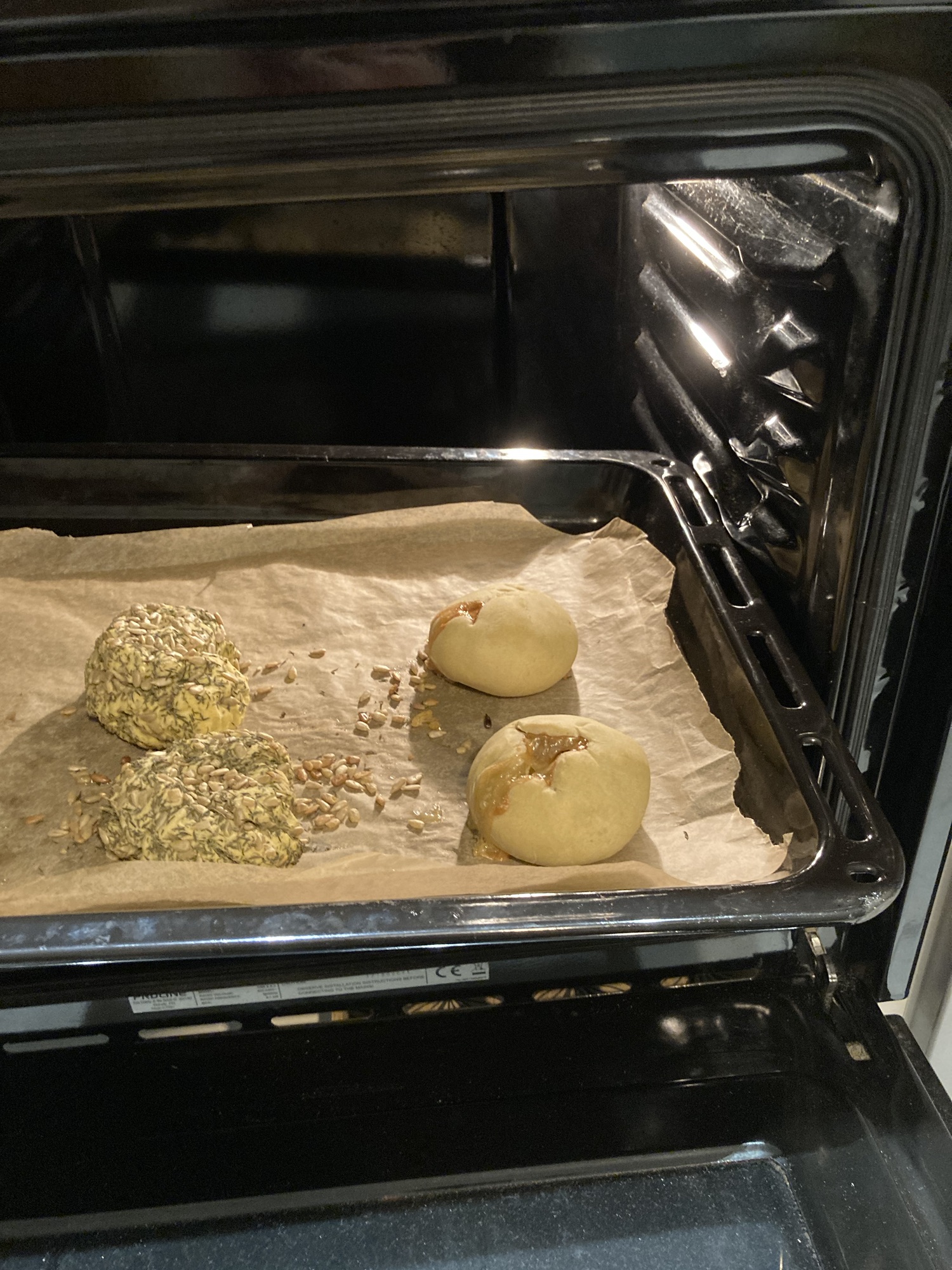 Sur une plaque de cuisson dans un four sont disposés quatres pains garnis: à gauche, deux complètement recouverts de thym et de graines de tournesol; à droite, deux boules simples dont la croûte n’a rien de particulier.