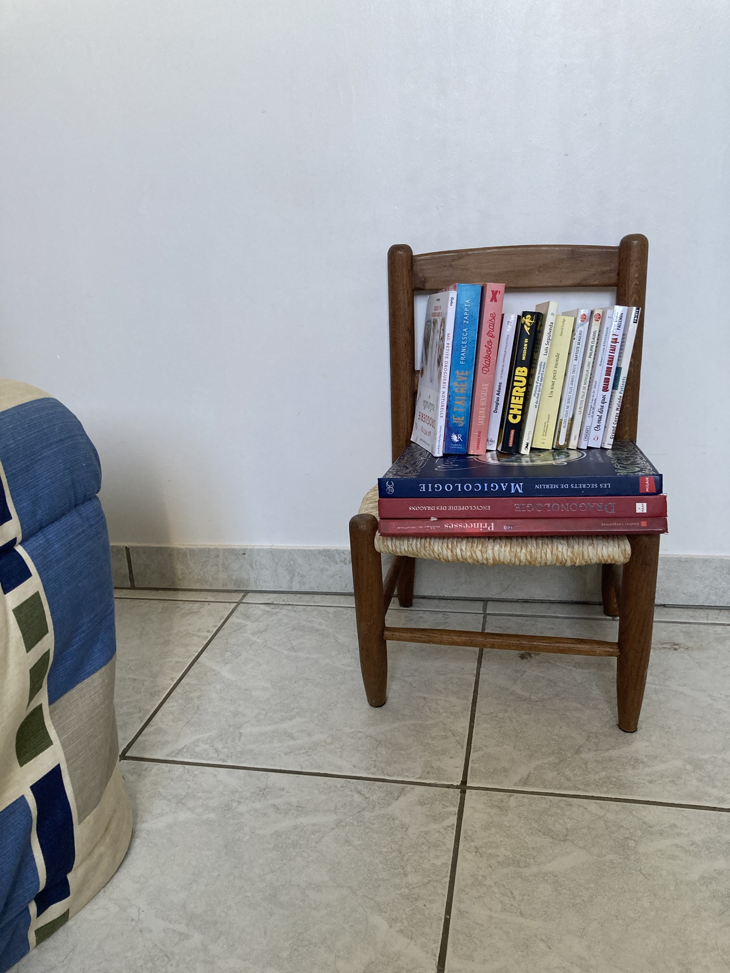 Sur une petite chaise en bois et paille sont disposés plusieurs livres.