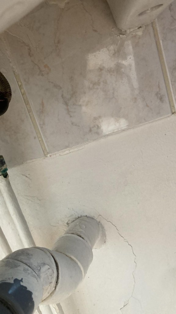 Vue des tuyaux sous un lavabo. On voit deux tuyaux flexibles en métal avec des rainures. L’un d’eux semble boursoufflé: le flexible en métal a l’air déchiré et le tuyau à l’intérieur est gonflé.
