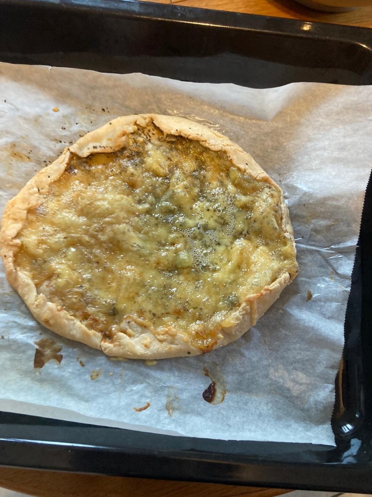 Une pizza maison aux fromages encore sur la plaque de cuisson.